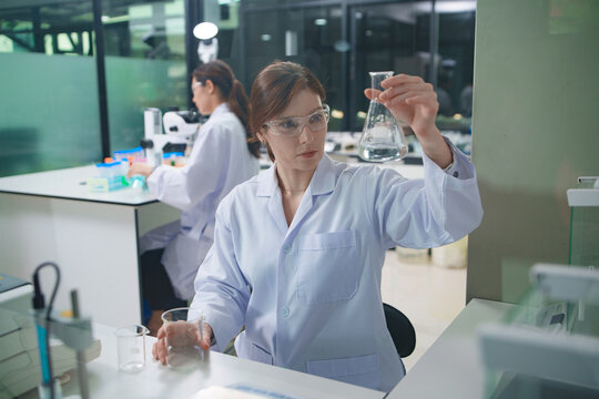 Laboratory Technician Analyzing Samples with Flask in Chemistry Lab