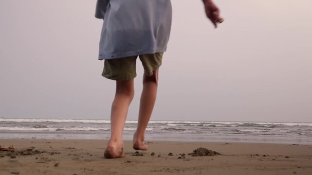 Child run barefoot toward ocean's edge. Soft light washes over quiet shoreline