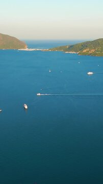 Vertical video. Marmaris, Turkey. Marmaris Bay, a deeply indented natural harbor enclosed by pine-covered peninsulas and forested mountains, aerial view at golden hour with scattered yachts and warm 