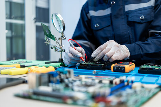Technician testing an electronic circuit board at a workbench with tools, meter and magnifier in a clean repair lab, showing precision, maintenance and technology work.