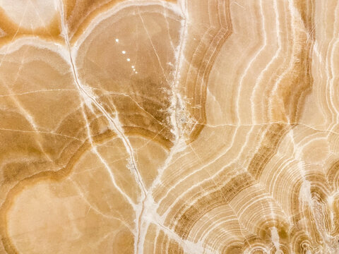 Full frame abstract texture of polished beige and brown onyx marble stone surface with natural wavy veins