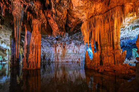 Illumined stalactites and crystal-clear subterranean lake inside Neptune's Grotto on Cape Caccia near Alghero in Sardinia, Italy