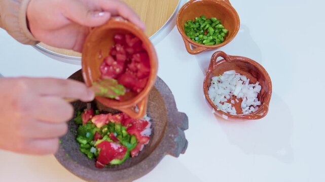 Chef preparing traditional mexican guacamole in a molcajete