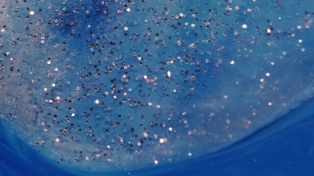 Glitter paint liquid. Marble ink. Defocused blue color water vivid wave round sequins sparkling texture floating on abstract acrylic art background.