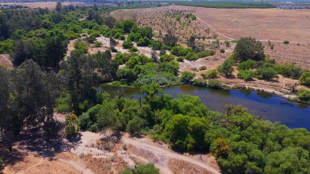 Panning Aerial Drone Shot Right to Left Over San Joaquin River With Trees Bushes and Hiking Trails in Fresno California
