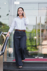 Fototapeta premium Young woman walking down stairs talking on phone