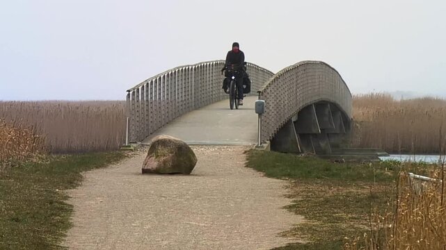 Cyclist with touring bags riding on a bridge in Denmark