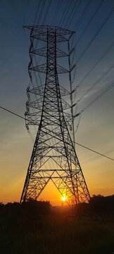 poweHigh voltage electricity pylon against vibrant sunset skyr lines at sunset