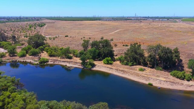 Descending Aerial Drone Shot Over San Joaquin River With People Swimming Trees Hiking Trails and Power Lines in Fresno California