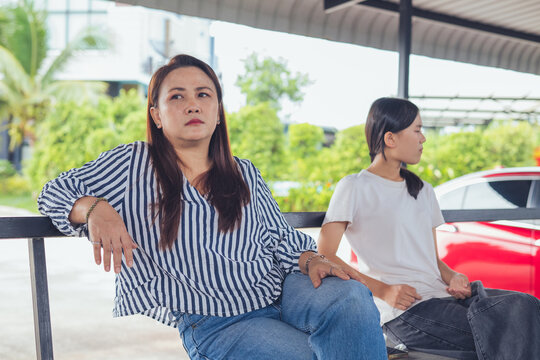 Depressed and stressed Asian middle-aged woman sitting lonely on a bench with head in hands inside an industrial background. Concept of financial crisis, business bankruptcy, debt pressure, mental hea