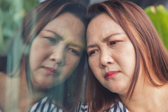 Sad and depressed Asian middle-aged woman facing emotional stress and anxiety inside a lifestyle environment. Concept of severe mental health crisis, burnout syndrome, depression, business failure, de