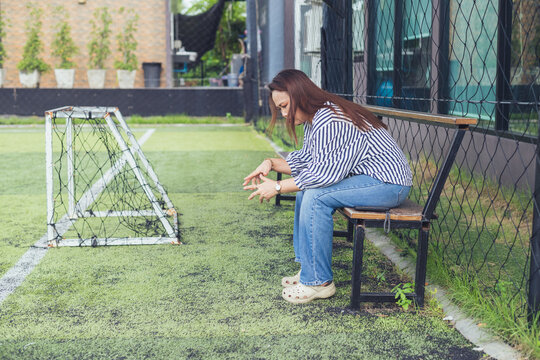 Sad and depressed Asian woman sitting lonely on a bench with anxious expression facing emotional stress. Concept of severe mental health crisis, chronic stress, depression, midlife crisis, personal pr
