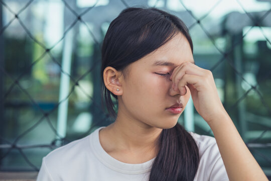 Sad and depressed Asian teenager girl closing her eyes with hand on face facing severe emotional stress. Concept of youth mental health crisis, teenage depression, chronic anxiety, burnout syndrome, p