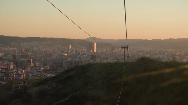 Dajti Express cable car descending towards urban city in Tirana, Albania, sunset