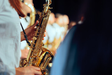 Obraz premium Female Saxophonist Holding Shiny Instrument Close Up Profile View. Young woman in white uniform shirt holds brass saxophone during musical band performance 