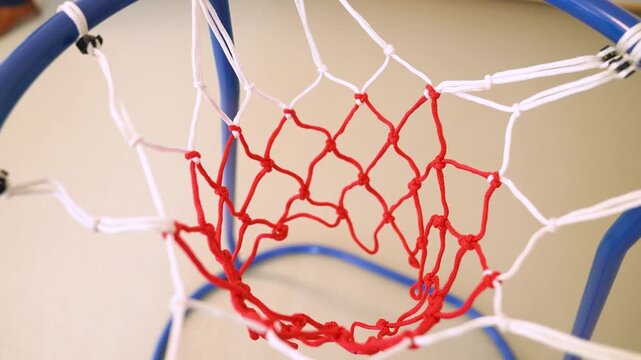 Blue basketball rim and a classic red and white net swaying after a ball goes through it