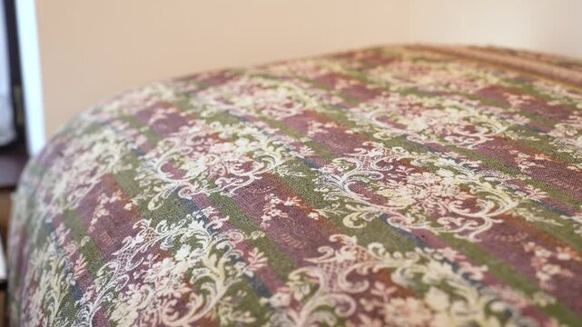 Close up view of a traditional bedspread with an ornate, woven floral damask pattern