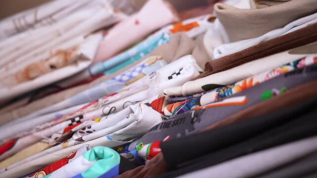 Colorful patterned and solid cotton textiles stacked on a shelf in a design studio workshop