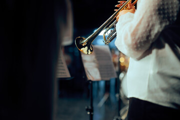 Musician Playing Shiny Trumpet Close Up During Concert Performance. Trumpeter in white shirt holds brass wind instrument reading music on stage © nicoletaionescu