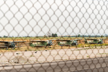 Decommissioned Soviet biplanes are stored behind a fence at an airfield in Kyrgyzstan. © Natalia