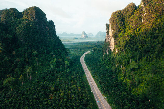 Aerial View of Scenic Green Road Cutting Through Limestone Mountains in Krabi