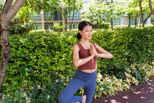 Asian woman doing yoga pose on yaga mat in park