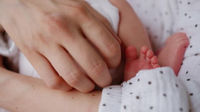 Tender hands of a mother carefully touching the small feet of her newborn child, a warm, affectionate moment highlighting the beauty of maternity, family connection, and unconditional