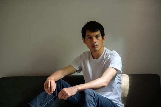 Young Man in a White T-Shirt Relaxing on a Couch in Natural Light
