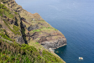 Obraz premium Atlantic Coast on San Miguel Island, Azores, Portugal. Rugged cliffs overlooking the ocean. Lush green vegetation on steep slopes. Clear blue waters and distant horizon.