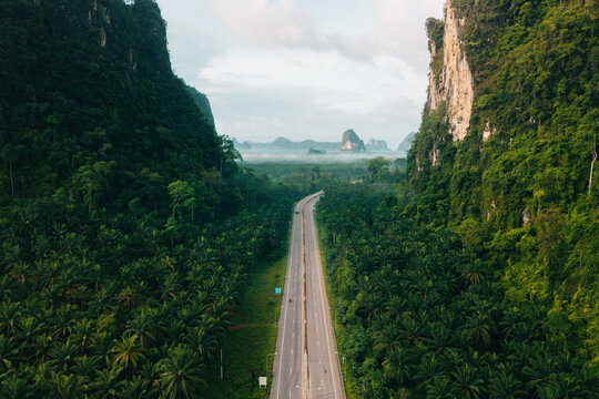 Aerial View of Scenic Green Road Cutting Through Limestone Mountains in Krabi