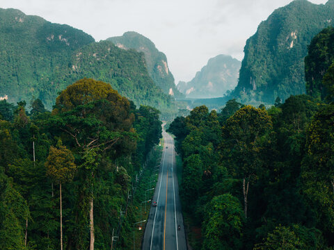Scenic Straight Highway Through Dense Jungle and Misty Mountains