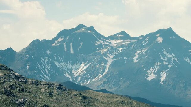 Snow covers the peaks of tall mountains in a remote area. The landscape shows rocky hills in the foreground and a clear blue sky above. This scene captures the beauty of nature.