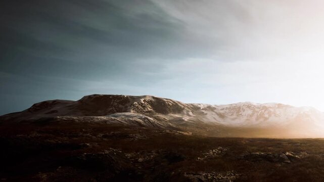 Sunrise casts light over snow covered mountains in winter. The scenery shows rocky terrain and a clear sky with soft colors blending together in the background.