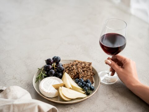 Comer queso, fruta y galletas con una copa de vino en una mesa