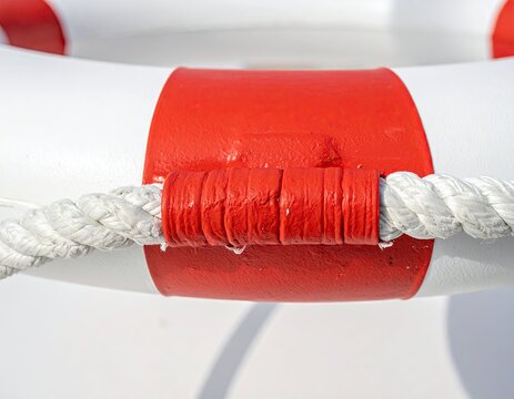 Close up of a red and white life preserver ring with rope detail.
