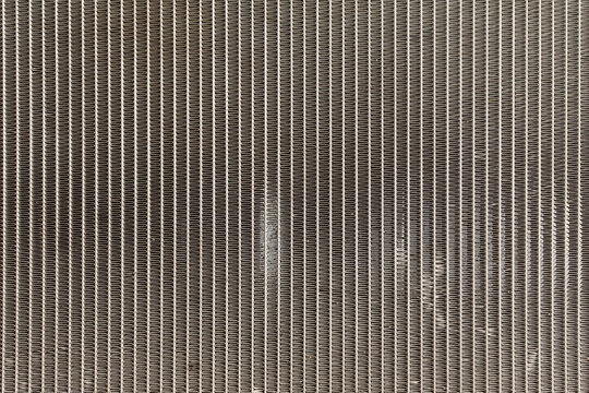 Close up of metal radiator cooling fins repeating industrial pattern detailed heat exchanger surface for engineering manufacturing background mechanical design