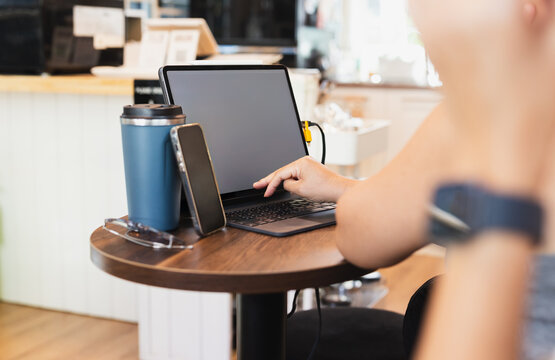 Over shoulder view of woman using a tablet on coffee shop table.