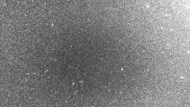 Close up abstract shiny silver glitter background with bright glowing sparkle particles. Glittering silver texture surface with elegant shimmer effect. Blank shiny silver glitter texture background.