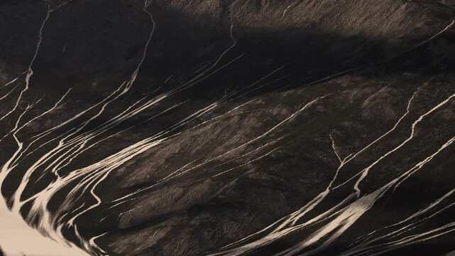 A vast area displays long lines and patterns on the surface. The setting shows dark soil and light streaks in afternoon light. Minimal vegetation is visible in this remote location.