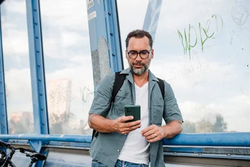 Bearded cyclist using phone while waiting for bus. © Halfpoint