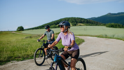 Fototapeta premium Active senior couple exploring nature on electric bicycles