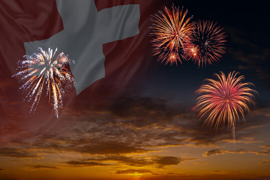 Waving National flag of Switzerland and holiday fireworks on evening sky