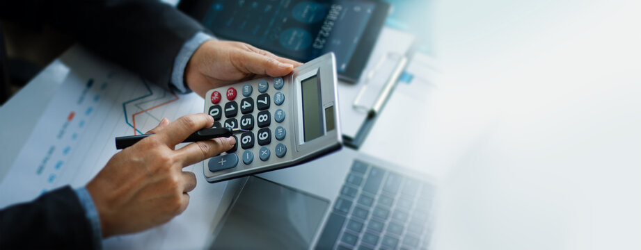 Businessman using calculator and laptop for do math finance in office, Business working of tax, Accounting, Statistics and analytics plan business growth and Strategy of investment.