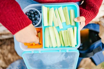 Close up of child hand taking carrot stick from healthy lunch box © Cavan