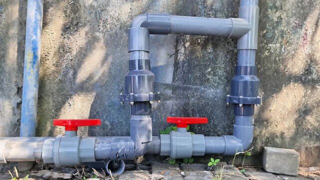 PVC ball valves with red handles connected to grey plastic water pipes for fluid flow control