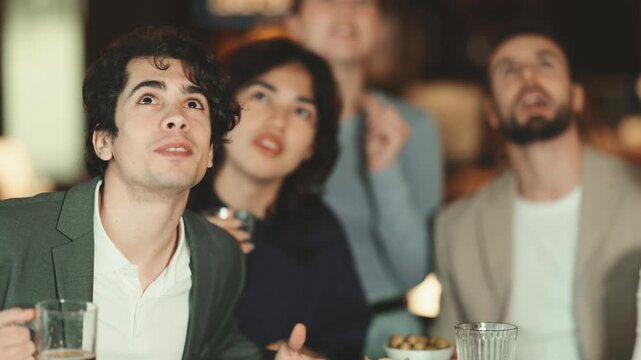 Group of male and female friends celebrate their favorite team's victory during sports match in bar