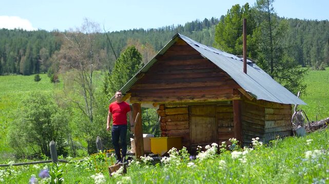 A cinematic wide shot of a focused athletic male traveler holding a woodcutting axe and standing on a stump outside an authentic Altai log cabin.