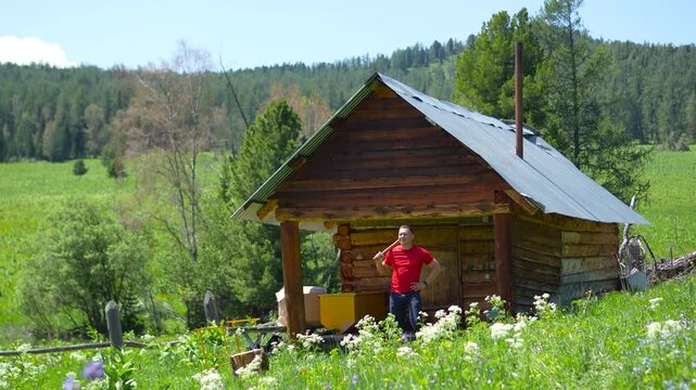 A cinematic wide shot of a focused athletic male traveler holding a woodcutting axe on his shoulder near an authentic Altai log cabin.