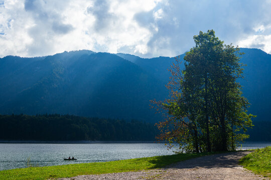 Mountai landscape with forest and lake under the cloudy sky and the sunbeams