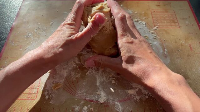 hands kneading cookie or cake dough in bright sunlight. Homemade baking